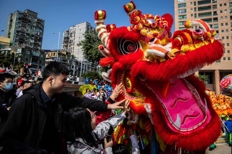 Pedestrians touch a head of a dragon during celebrations in Macau on the first day of the Lunar New Year of the Dragon.  AFP