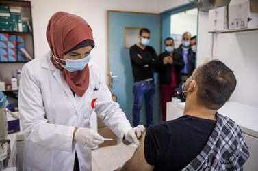 A Palestinian nurse administers a dose of Moderna’s Covid-19 vaccine to a fellow health worker in the West Bank city of Bethlehem. Bloomberg