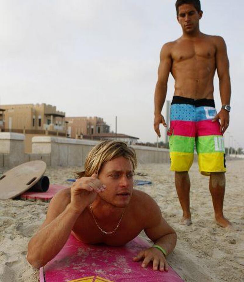 Daniel Van Dooren, left, and Scott Chambers of Surf Dubai demonstrate surfing techniques to students on the beach.
