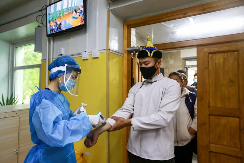 A man wearing a face mask has his body temperature checked as he arrives to vote at a polling station in Ulaanbaatar, the capital of Mongolia.  AFP