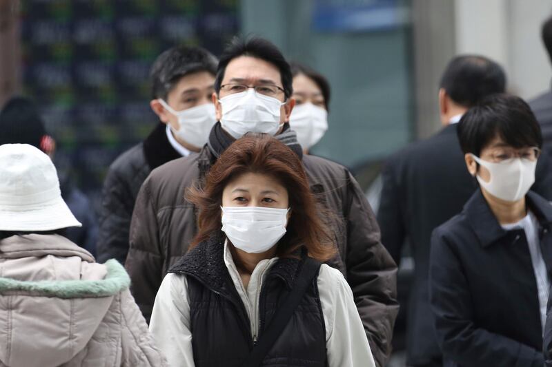 People wearing protective face masks cross a street in Tokyo, Monday, Feb. 17, 2020. Chinese authorities on Monday reported a slight upturn in new virus cases and hundred more deaths for a total of thousands since the outbreak began two months ago. (AP Photo/Koji Sasahara)