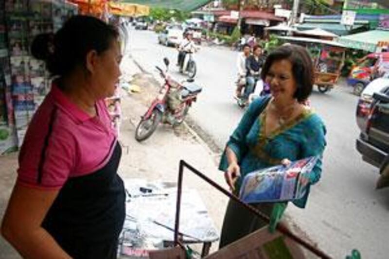 Mu Sochua, right, who is facing defamation charges, speaks to a news-stand vendor in Cambodia.