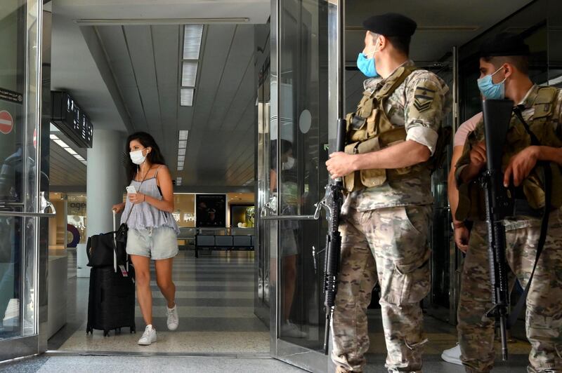Lebanese soldiers stand guard as a woman leaves Rafik Hariri international airport during its re-opening in Beirut. EPA