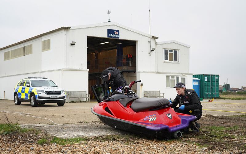 A jet ski is inspected by police officers after being brought in to Dungeness, Kent. Migrants trying to reach the UK across one of the world’s busiest shipping lanes appear to have used a 25-year-old jet ski and kayaks as record numbers try to reach Britain. PA