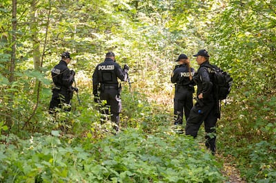 Police search a wooded area after the discovery of the body last August. Getty 