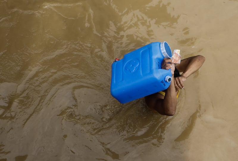 A resident carries a water container and money while wading through flood water caused by typhoon Noru in Bulacan province, north of Manila, Philippines, on September 26, 2022.  EPA