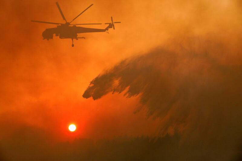 A helicopter makes a water drop as a wildfire burns north of Athens, Greece.  Giorgos Moutafis / Reuters