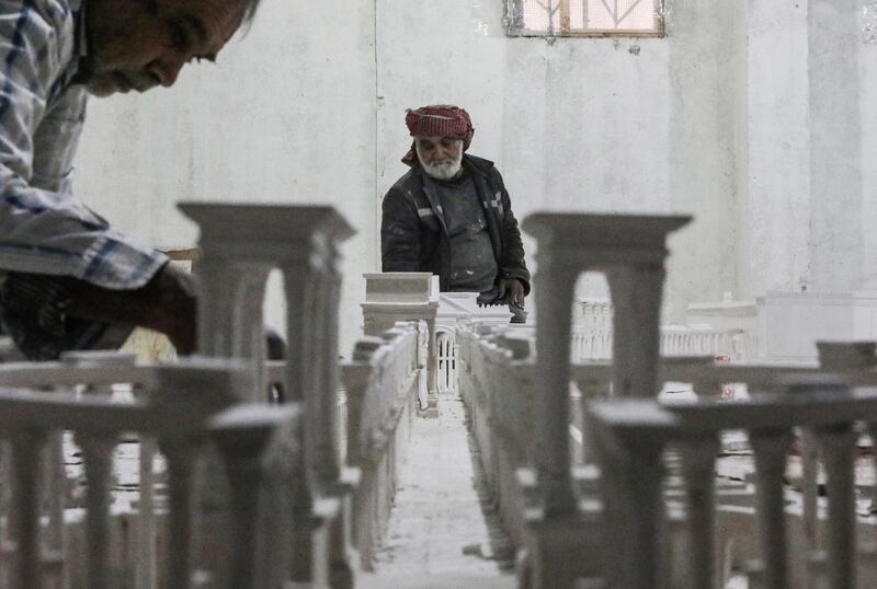 Ali Saleh (L), a 58-year-old displaced Syrian originally from Palmyra, builds from memory a wood and gypsum model of a prominent archaeological landmark of his home city that was heavily damaged by Islamic State (IS) militants, at a workshop home in the rebel-held city of al-Bab northwest of Aleppo in northern Syria on January 14, 2021. - Ten years of Syria's civil war have robbed Saleh of his home in the desert city, his three sons and daughter, and the last of his poor hearing, his family says. But he still vividly remembers Palmyra's ruins, where he accompanied restoration and excavation teams for 25 years, before the Islamic State group overran the city in 2015. (Photo by Bakr ALKASEM / AFP)