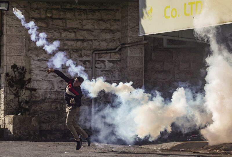 A Palestinian protester hurls a tear gas canister back at Israeli security forces during confrontations in the centre of the occupied West Bank city of Hebron. AFP
