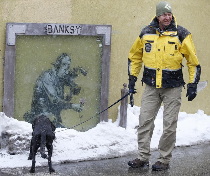 epa05732385 A policeman and a bomb sniffing dog checks out a snow pile next to a "Banksy" painting along Old Main Street on the first day of the 2017 Sundance Film Festival in Park City, Utah, USA, 19 January 2017. The festival runs from 19 to 29 January.  EPA/GEORGE FREY