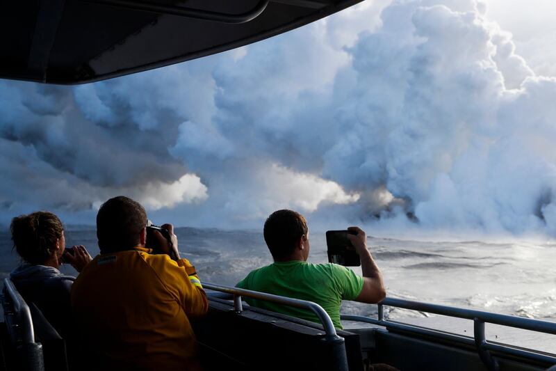 People take pictures as lava enters the ocean, generating plumes of steam near Pahoa, Hawaii. Jae Hong / AP Photo