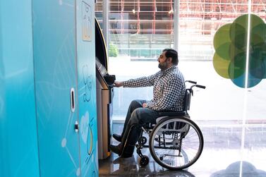 Mohammad Zeeshan uses an ATM, that has been adjusted to suit people who use wheelchairs, at Tanfeeth’s office in Dubai. Reem Mohammed / The National