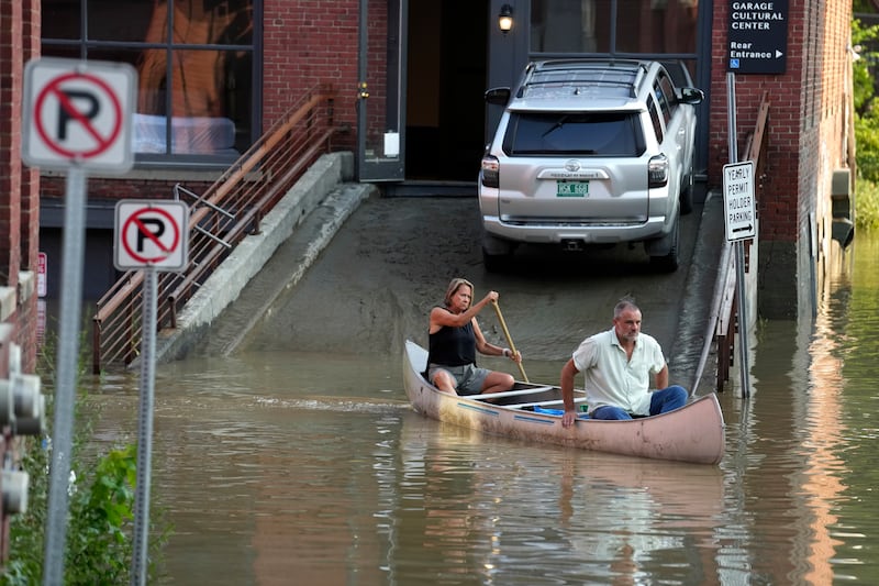A couple use a canoe to retrieve surgical supplies from a flood-damaged veterinary centre in Montpelier. AP