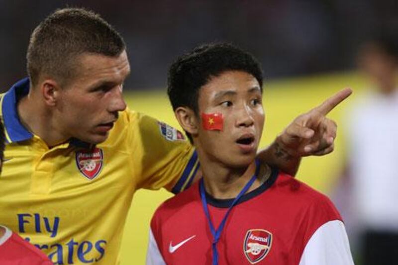 Lukas Podolski, the Arsenal forward, talks to fan Vu Xuan Tien, dubbed 'The Running Man', ahead of their friendly against Vietnam in Hanoi. Chris McGrath / Getty Images