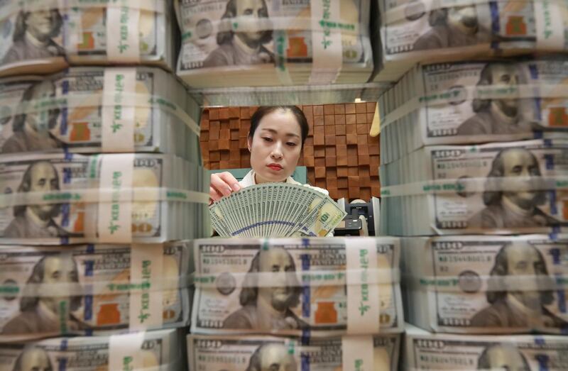 A clerk scrutinizes 100 dollar bank notes at the headquarters of KEB Hana Bank in Seoul, South Korea. Yonhap / EPA