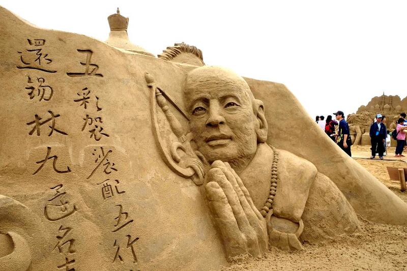 Visitors walk past a sand sculpture named Xuan Zang. AFP
