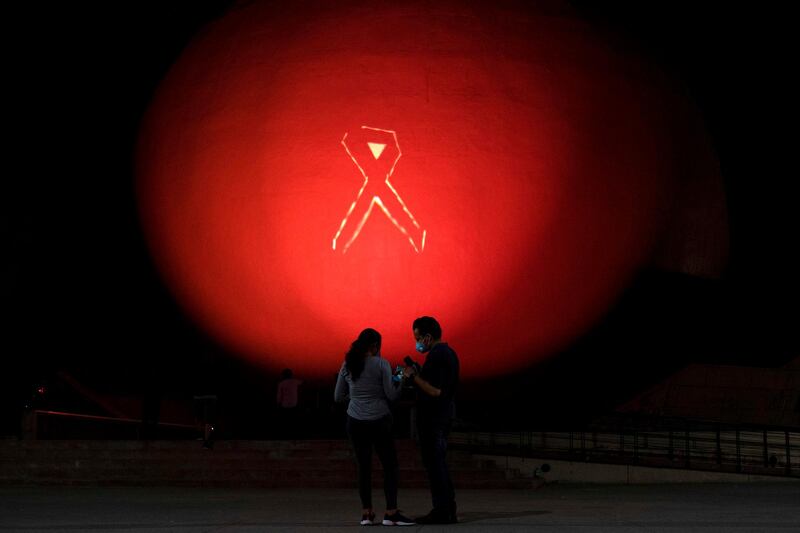 A couple stands outside the Tijuana Cultural Centre (CECUT) as its dome is illuminated in pink as part of the Breast Cancer Awareness Month, in Tijuana, Baja California State, Mexico, on October 19, 2020. / AFP / Guillermo ARIAS
