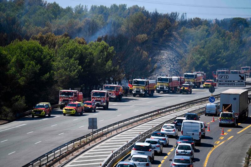 Firefighters work on the closed A55 highway to tackle the fast-moving blaze. AFP