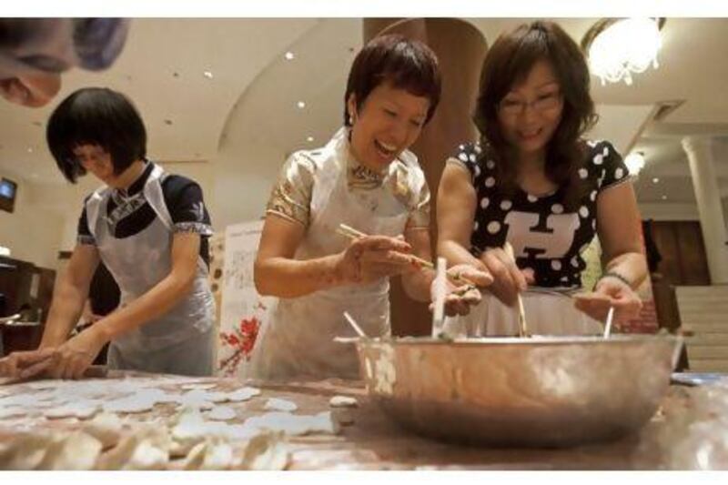 Fang Lee, Lianna Cai and Yanny Hu make dumplings at the Confucius Institute yesterday.