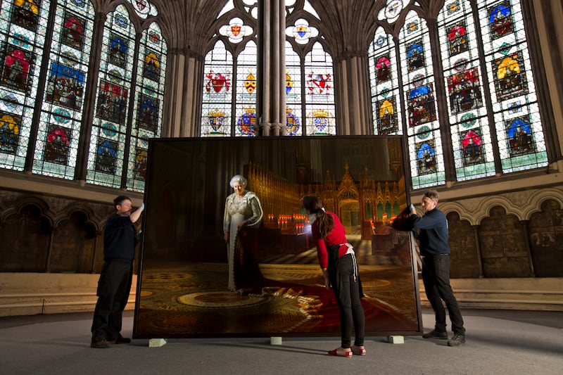 Conservators conduct a condition report on a portrait of the queen before it is placed inside the Chapter House at Westminster Abbey, in 2013. Getty Images