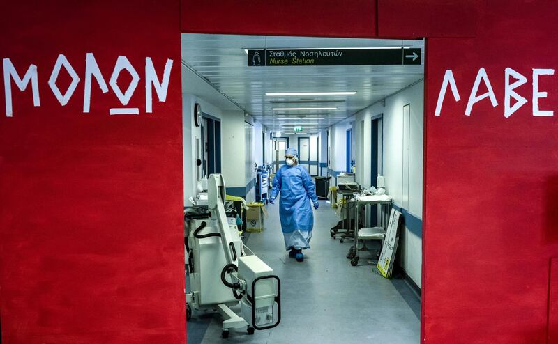 A member of the medical team at the Nicosia General Hospital where patients suffering from the COVID-19 caused by the novel coronavirus are treated, walks from the intensive care unit toward the monitoring and recovery section, as a red gate is seen outside bearing the Ancient Greek inscription "Molon labe", in the Cypriot capital on April 29, 2020. - The Ancient Greek phrase "Molon labe" is attributed to King Leonidas I of Sparta before the battle of Therompylae (480 BC) during the Greco-Persian Wars, when the Persians reportedly asked the Greek side to surrender their weapons prompting the reply "come and take them" as a sign of defiance. (Photo by Iakovos Hatzistavrou / AFP)