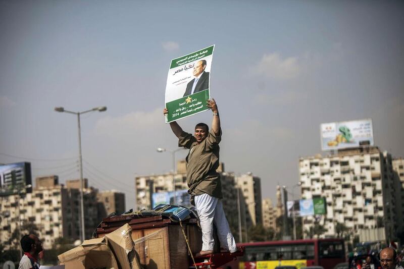 A supporter of Egyptian ex-army chief and leading presidential candidate Abdel Fattah El Sisi stands on the top of a vehicle holding up a poster bearing Mr El Sisi's portrait on May 23 in Cairo. 

