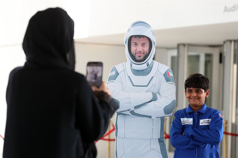 A pupil has a picture taken alongside a cutout of Sultan Al Neyadi.  