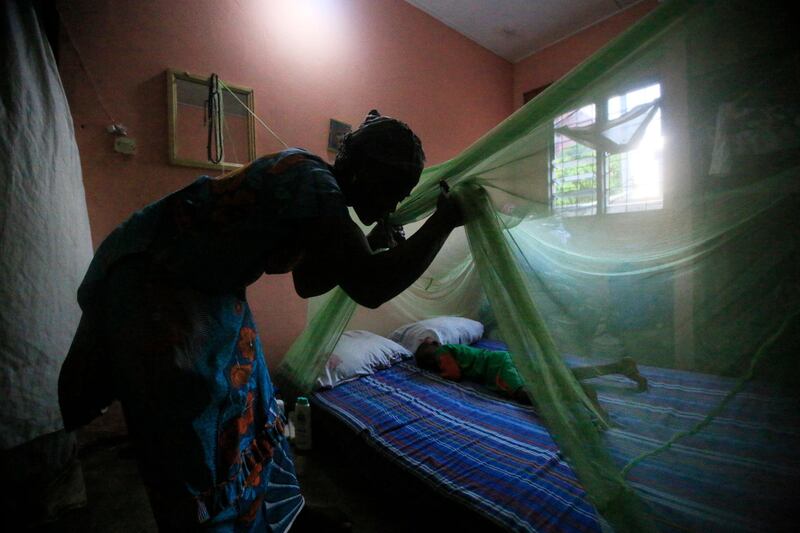 epaselect epa06689943 A woman installs a mosquito net over her child in Abidjan, Ivory Coast, 24 April 2018. World Malaria Day is observed on 25 April each year to recognize the global efforts to control Malaria, it was established in May 2007 by the World Health Organization (WHO).  EPA-EFE/LEGNAN KOULA