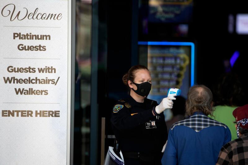 A security official checks the temperature of a man at the entrance to the Viejas Casino and Resort as it reopens in Alpine, California, US. AP Photo
