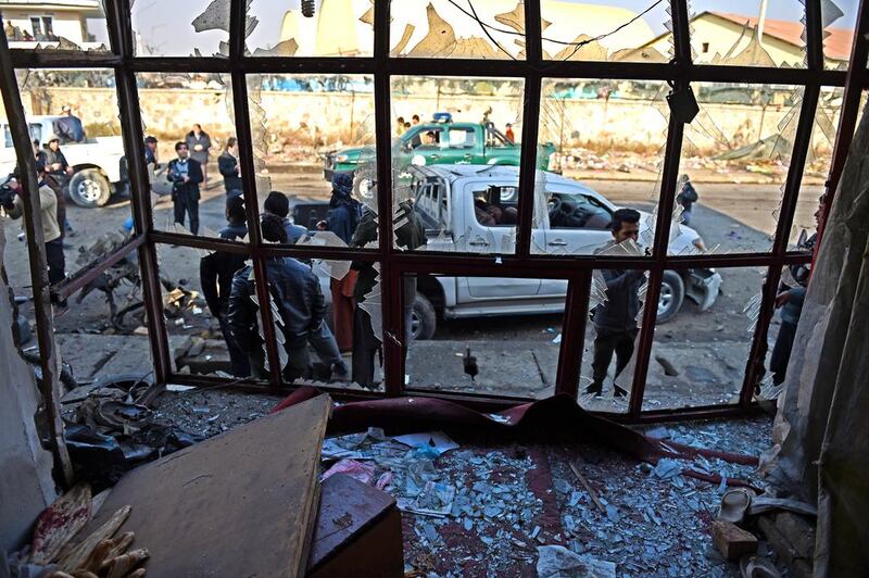 Afghan troops look through the broken windows of a bakery at the site of a suicide car bombing near the airport in Kabul on December 28, 2015. Shah Marai / AFP