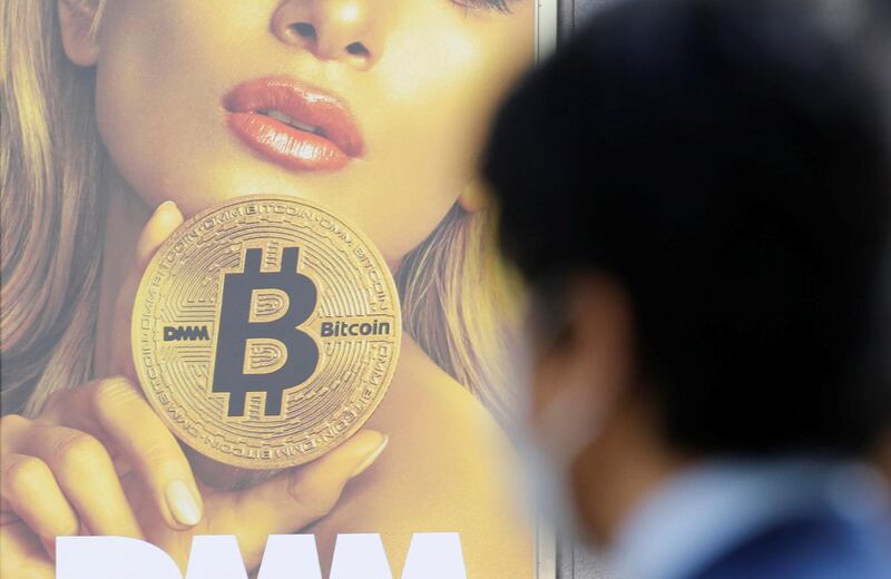 A man stands near an advertisement of a cryptocurrency exchange in Tokyo, Japan March 30, 2018. Picture taken March 30, 2018.  REUTERS/Toru Hanai