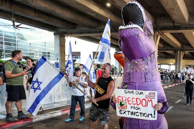 A demonstrator in a dinosaur suit marches at Ben Gurion Airport near Lod. AFP
