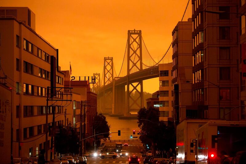 The San Francisco Bay Bridge is seen along Harrison Street under an orange smoke-filled sky in San Francisco, California.  AFP