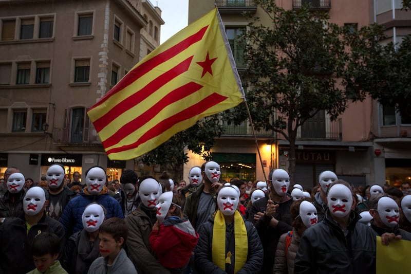 People wear white masks in support of Catalonian politicians jailed on charges of sedition and condemning the arrest of Catalonia's former president, Carles Puigdemont, in Germany, during a protest in Figures, Spain, Thursday, April 5, 2018. A German court has ruled that former Catalan leader Carles Puigdemont can be released on bail pending a decision on his possible extradition to Spain. (AP Photo/Emilio Morenatti)