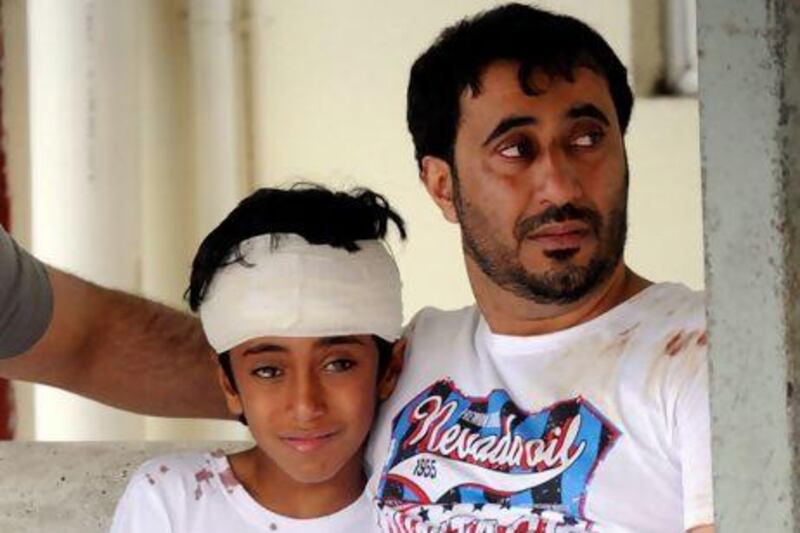 Ali Mohamed Amer, whose pregnant wife and 13-year-old daughter died in the accident, with his eldest son, Mohammed, 11, at Tapah Hospital where the injured were treated. Courtesy FotoBernama