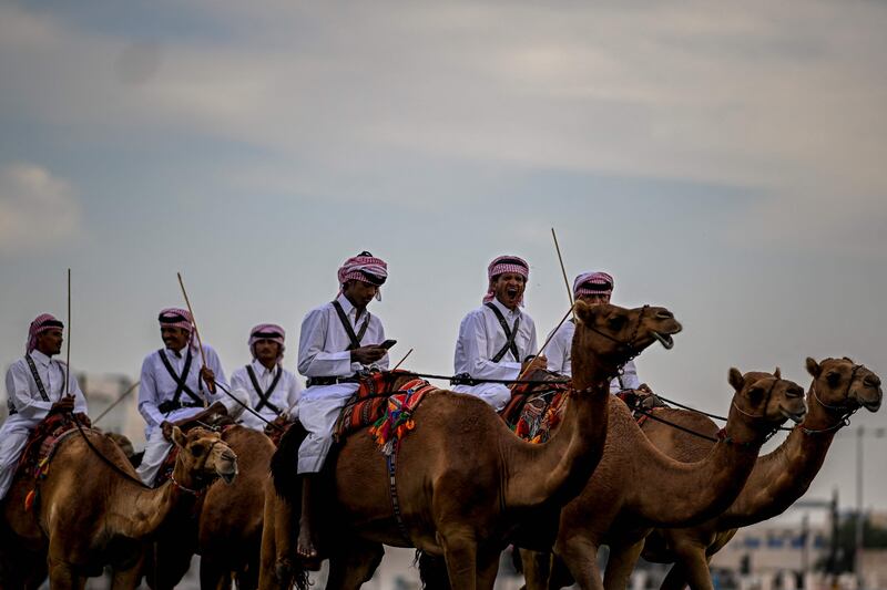 Men ride camels in Doha. AFP