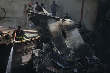 A firefighter sprays water on the wreckage of a Pakistan International Airlines aircraft after it crashed in a residential area of Karachi. AFP