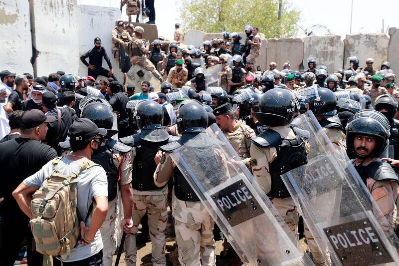 Security forces gather as supporters of Mr Al Sadr bring down concrete barriers leading to the capital Baghdad's high-security Green Zone.  AFP