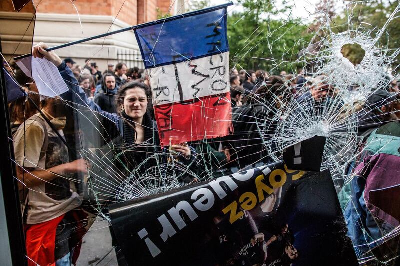 A protester holds a French tricolore flag with an anti-Macron slogan outside a destroyed McDonald's fast food restaurant. Unions called for marches to protest against government reforms in the public services.  EPA/CHRISTOPHE PETIT TESSON