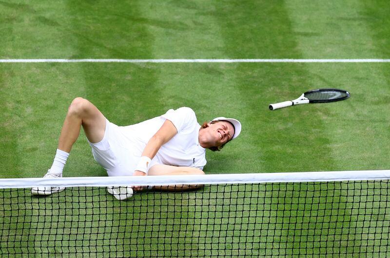 Italy's Jannik Sinner clutches his ankle after twisting it in a fall. Reuters