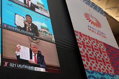 Monitors showing U.S President Donald Trump, left, hold up declaration together with other leaders attending the first virtual Asia-Pacific Economic Cooperation (APEC) leaders' summit, hosted by Malaysia, in Kuala Lumpur, Malaysia, Friday, Nov. 20, 2020. Leaders from the Asia-Pacific Economic Cooperation forum have begun a virtual meeting to seek ways to revive their coronavirus-battered economies, with U.S. President Donald Trump participating for the first time since 2017. (AP Photo/Vincent Thian)