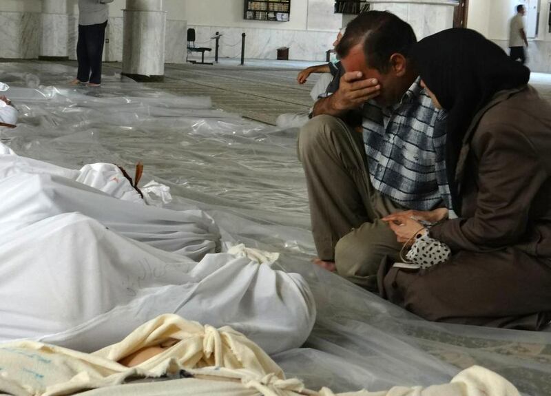 A photo image released by the Syrian opposition's Shaam News Network shows a couple mourning in front of victims of a toxic gas attack allegedly carried out by pro-government forces in eastern Ghouta in August last year. AFP / August 21, 2013