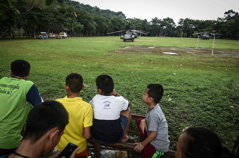 Villagers watch rescue preparations at the football field used by the missing football team near Tham Luang cave. Lillian Suwanrumpha / AFP