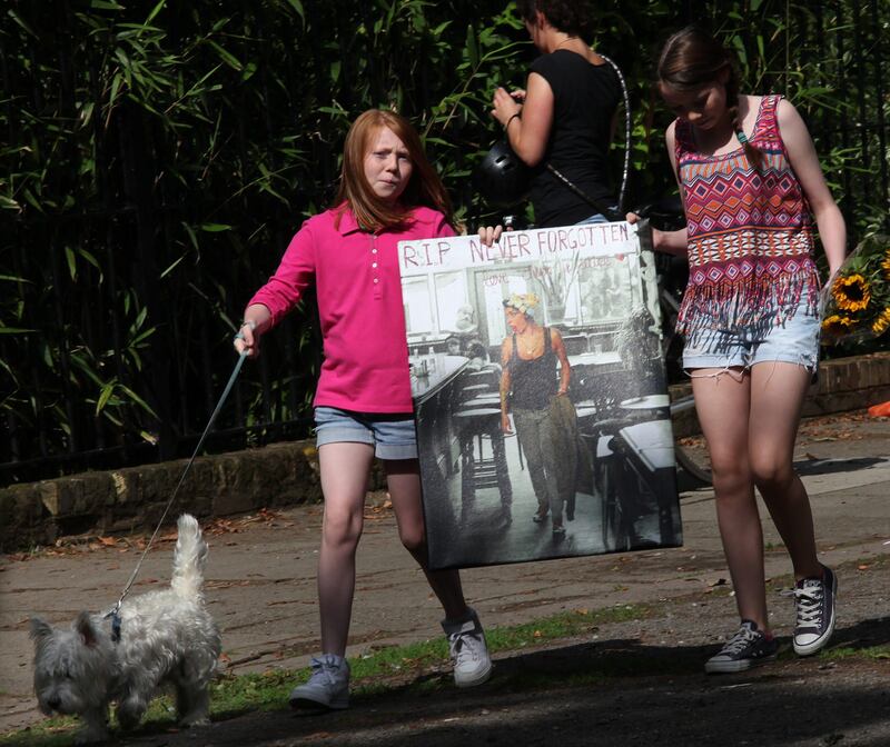 Girls carry a poster of Amy Winehouse on July 24, 2011 near the north London house in where pop star Amy Winehouse was found dead the previous day aged 27. Reports said the Grammy award-winning soul singer, with her trademark beehive hairstyle, overdosed on drugs but police refused to speculate on the cause of her death on Saturday, saying it remained unexplained.           AFP PHOTO / CARL COURT
 *** Local Caption ***  482760-01-08.jpg