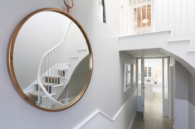 Reflection of foyer staircase in round mirror. Getty Images