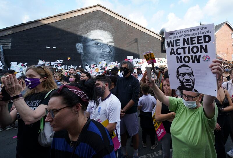 A protester holds up a banner bearing an image of George Floyd during an anti-racism protest in Manchester, England. AP