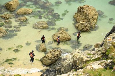 Police officers in wetsuits patrol the rocky shore between St Ives and Carbis Bay, Cornwall on June 10, 2021, ahead of the three-day G7 summit being held from 11-13 June.  G7 leaders from Canada, France, Germany, Italy, Japan, the UK and the United States meet this weekend for the first time in nearly two years, for the three-day talks in Carbis Bay, Cornwall. - 
 / AFP / Oli SCARFF
