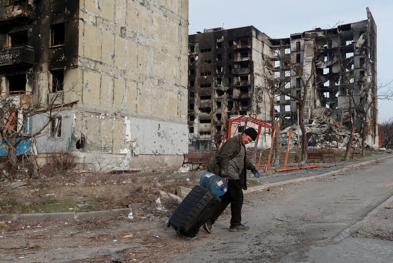 A resident passes apartment buildings destroyed by Russian attacks in the besieged southern port city of Mariupol, Ukraine. Reuters