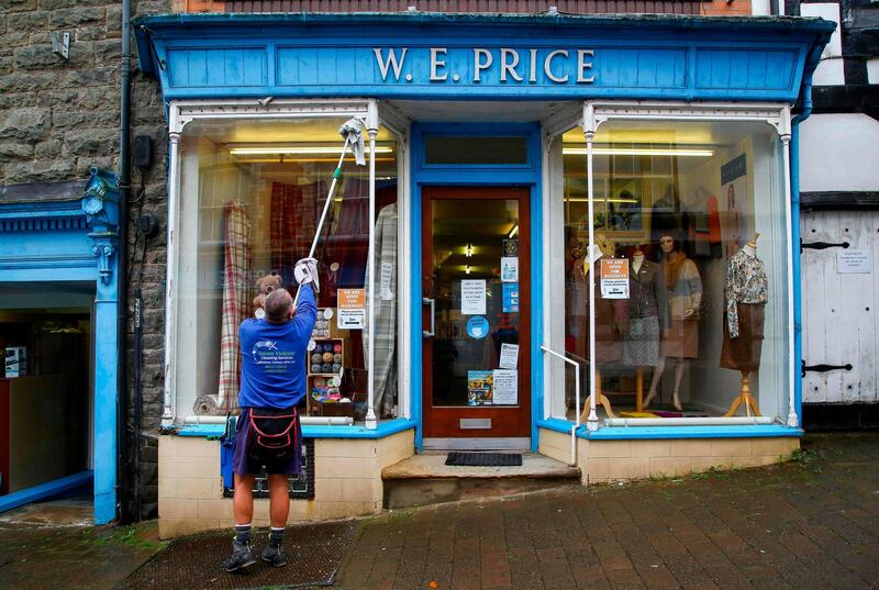 Window cleaner Simon Victress cleans windows of shops which will shut down for two weeks during Wales's firebreak lockdown. AFP
