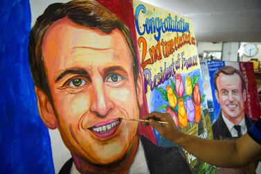 An artist gives final touches to a painting of French President and La Republique en Marche (LREM) party candidate for re-election Emmanuel Macron after his victory in France's presidential election, in Mumbai on April 25, 2022.  (Photo by Punit PARANJPE  /  AFP)